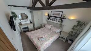 A bedroom with a bed, a desk, a wardrobe, and a mirror. - Hocking Cottage (Torquay)