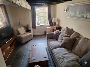 A living room with a sofa, armchair, coffee table, and a television.