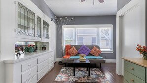 Una sala de estar con sofá, mesa de centro y aparador con objetos decorativos.