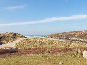 A coastal landscape with dunes, a beach, and a river.