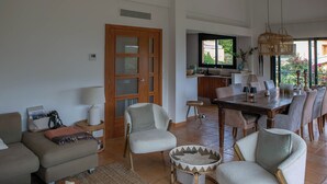 A spacious living area with a dining table, chairs, sofas, and a wicker chair.
