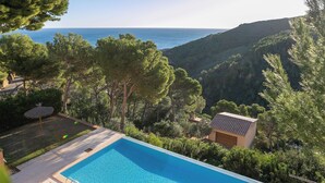 A swimming pool with a view of the sea and hills.