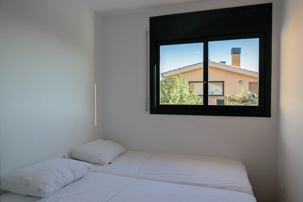 A single bed with white bedding in a room with a window.