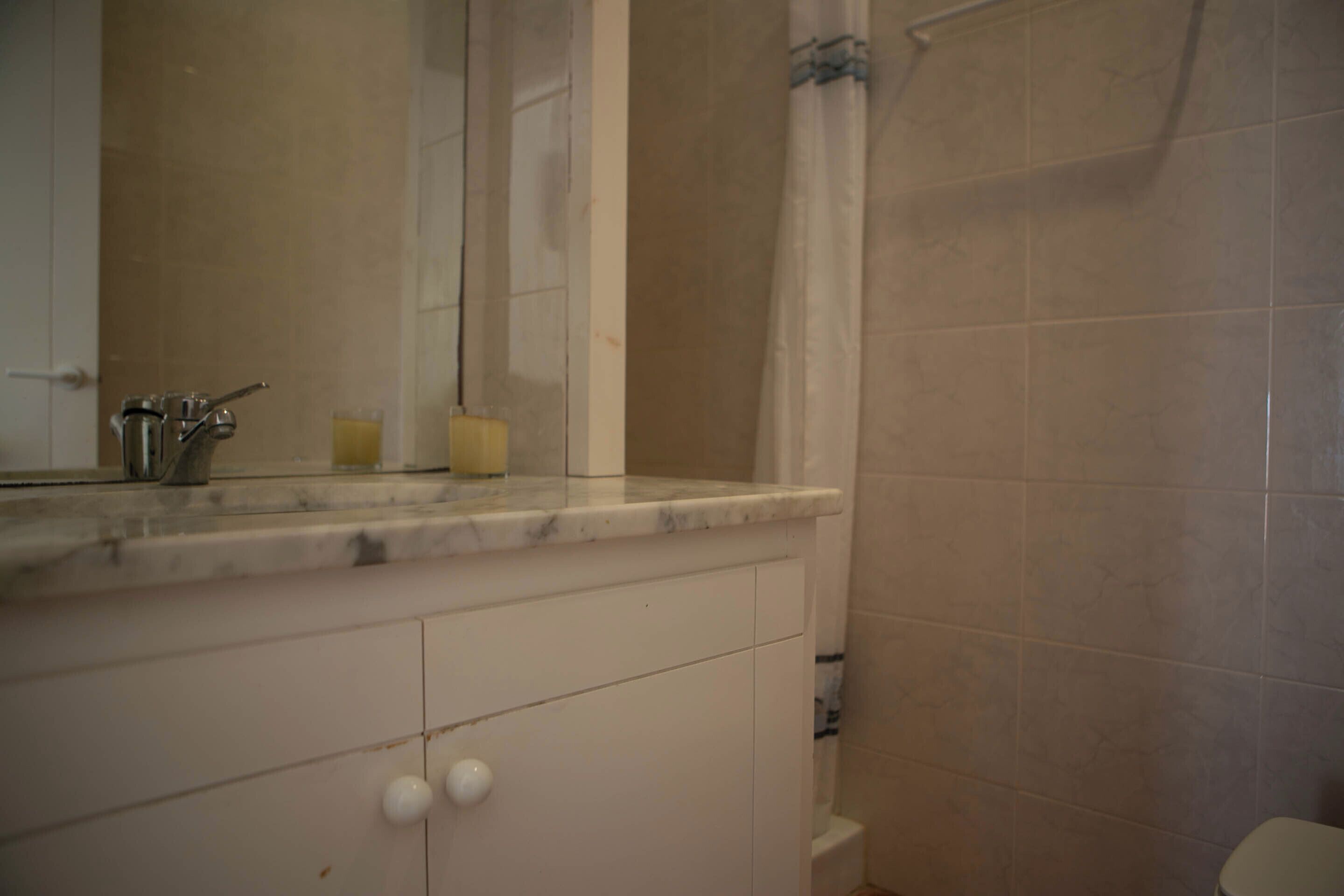 A bathroom with a marble countertop, a sink, a mirror, and a shower curtain.