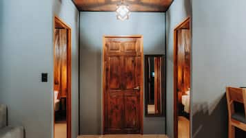 A hallway with a wooden door, a mirror, and a light fixture.