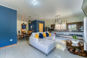 Una sala moderna con sofá, comedor, cocina y un amplio ventanal.