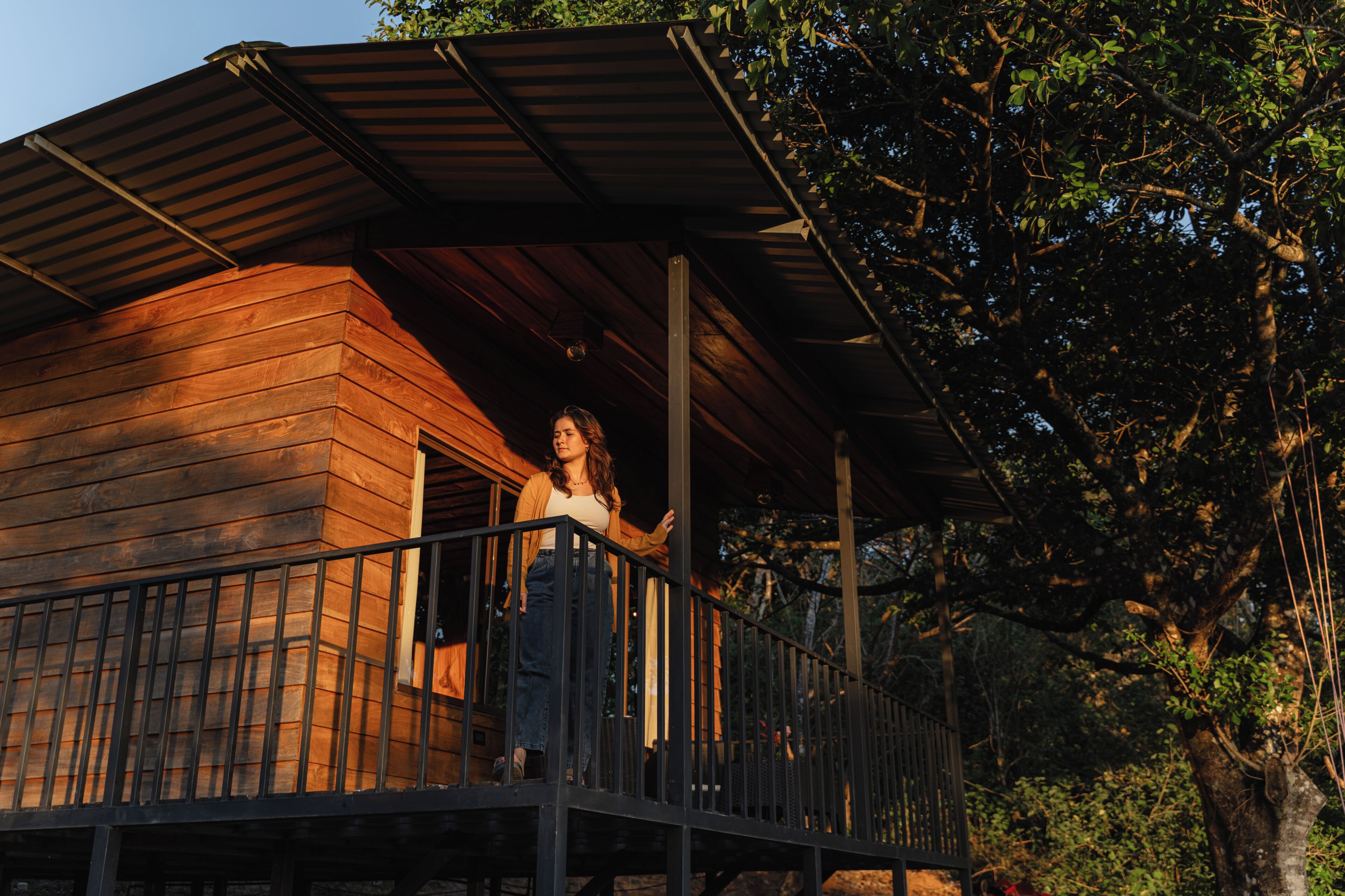 Une cabane en bois dotée d’un balcon, entourée d’arbres.