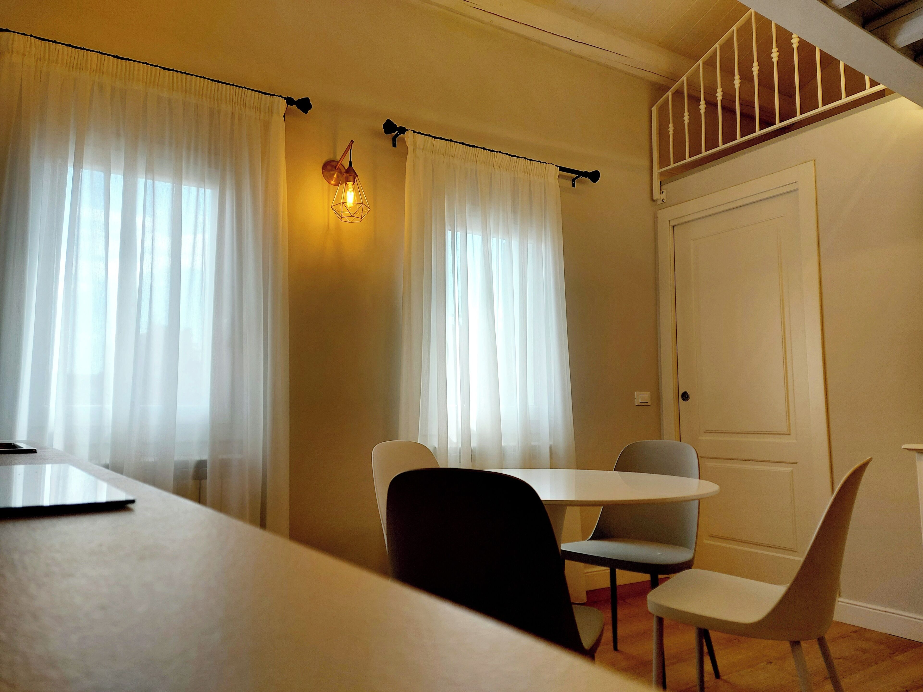 Una zona de menjador amb taula i cadires, una escala i una porta.
