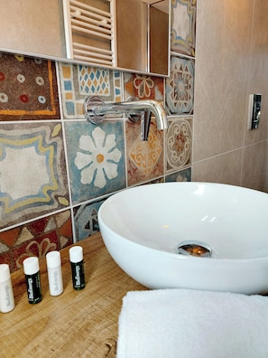 Un baño con un lavamanos blanco, azulejos coloridos y una encimera de madera.