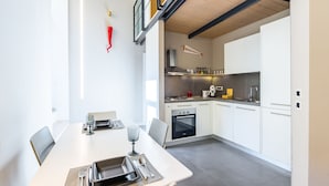 Een moderne keuken met witte kasten, een fornuis, oven en een wanddecoratie met vismotief.