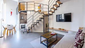 Een moderne woonkamer met een trap, een eethoek en een keuken.