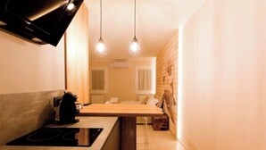 A compact kitchen with a built-in stove, wooden countertop, and pendant lighting. - Colibri House (Sottomarina)