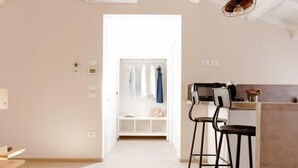 A modern kitchen with a bar area, a walk-in closet, and a hallway leading to a bedroom. - Colibri House (Sottomarina)