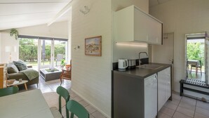 A modern kitchen with a built-in dishwasher, a small countertop, and a window overlooking a garden. - Holiday Home Near Petten Beach With Pool (Petten)