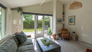 A modern living room with a sofa, coffee table, and chairs, a large window, and a door leading to a balcony. - Holiday Home Near Petten Beach With Pool (Petten)