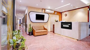Un espace d’accueil avec un canapé, des plantes en pot, un téléviseur à écran plat et un panneau indiquant : « TOWNHOUSE OAK Company, services proposés ».