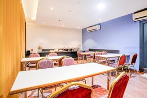A conference room with tables and chairs, a kitchen area, and an air conditioning unit on the wall.