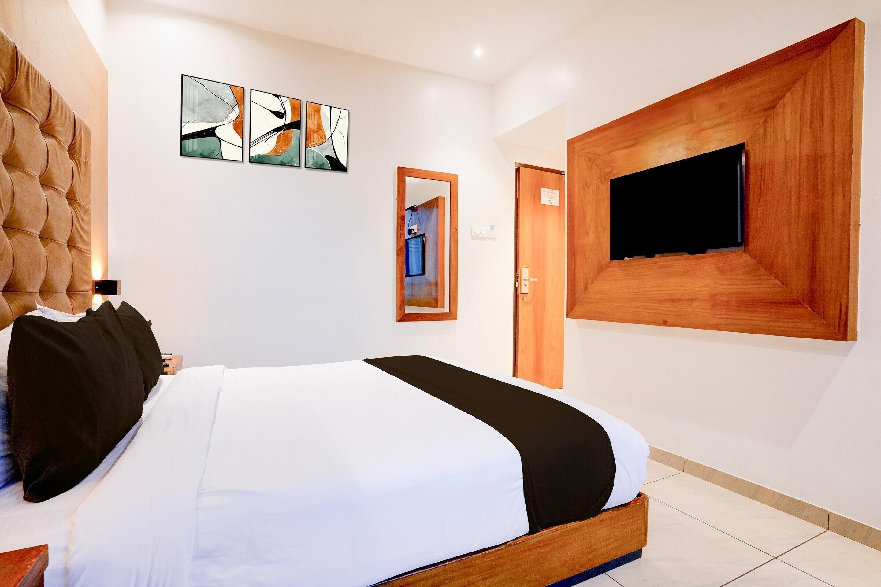 Un dormitorio moderno con una cama grande, un televisor montado y arte abstracto en la pared.