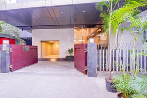 A hotel entrance with a covered walkway, a red gate, and potted plants.