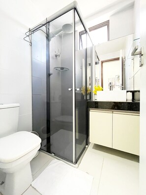 Een moderne badkamer met een douchecabine van glas, een toilet en een wastafel met spiegel.