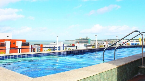 A rooftop pool with a city view, metal railings, and a tiled edge. - Cayenne By Day by Day (Joao Pessoa)