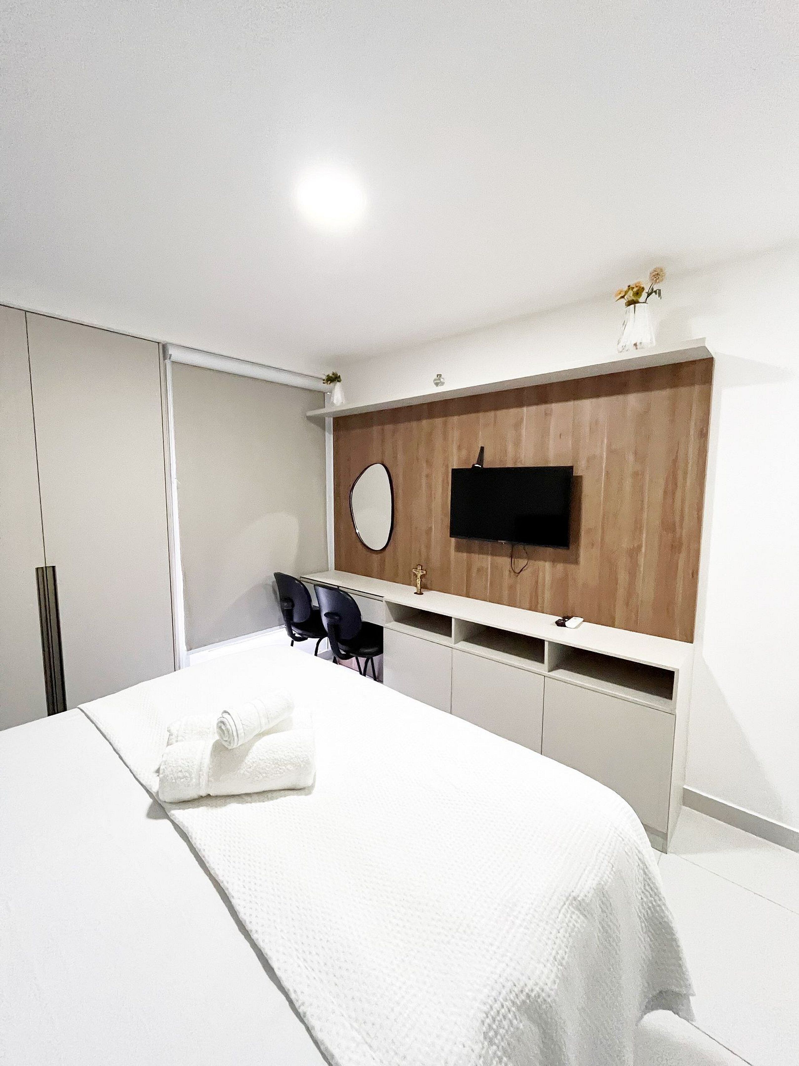 Een moderne slaapkamer met een bed, een bureau en een televisie bevestigd aan een houten wand.