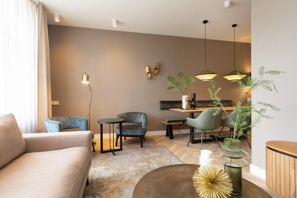 Una sala de estar moderna con un sofá, sillas, una mesita de centro y un comedor con mesa y sillas.