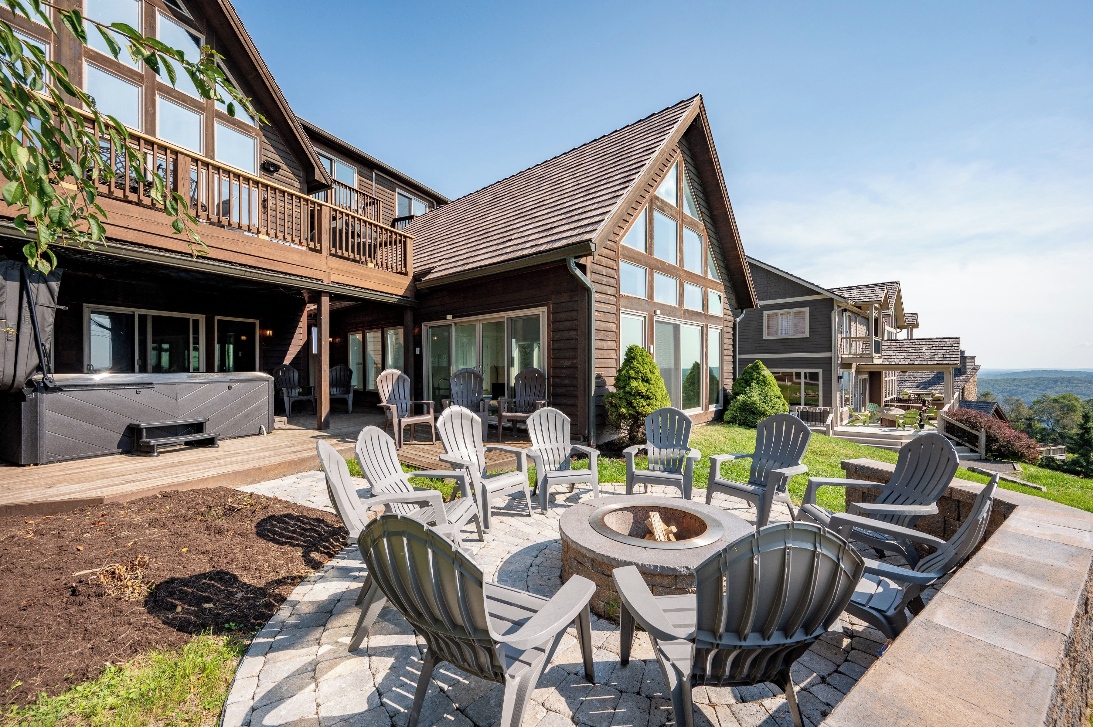 A wooden house with a deck, outdoor seating, and a fire pit.