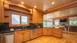 A modern kitchen with wooden cabinets, a granite countertop, stainless steel appliances, and a stone backsplash.