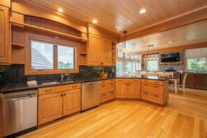 A modern kitchen with wooden cabinets, a granite countertop, stainless steel appliances, and a stone backsplash.