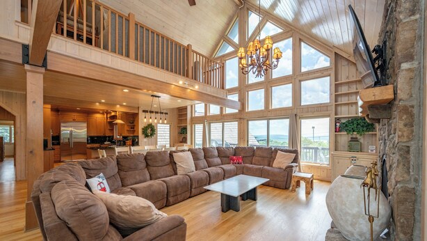 A spacious living area with a large sectional sofa, a coffee table, and a stone fireplace.