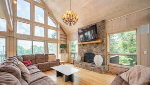 A spacious living room with a stone fireplace, large windows, and a cozy seating area.