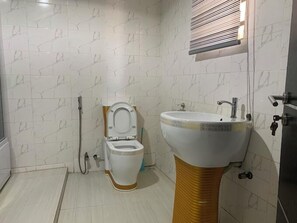 Egy fürdőszoba, amelyben WC, mosdókagyló és zuhanyzó található.