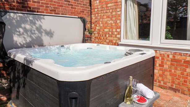 A hot tub in a backyard with a brick wall and a window. - Tennyson Grange (Bridlington)