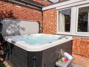 A hot tub in a backyard with a brick wall and a window. - Tennyson Grange (Bridlington)