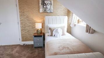 Un dormitorio con cama, mesita de noche, lámpara, una obra de arte en la pared y ventana con cortinas.