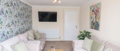 A living room with two sofas, a coffee table, a TV, and a door.