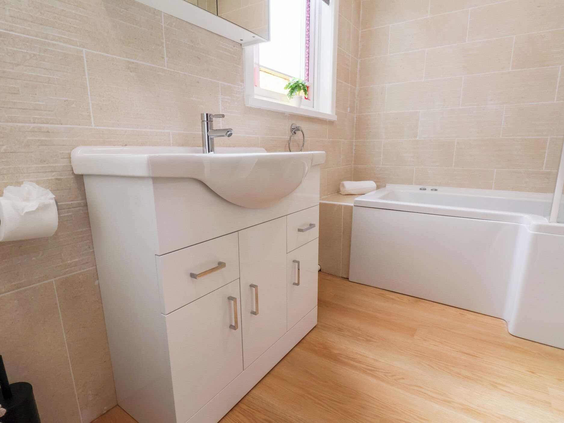 A modern bathroom with a white vanity, a sink, and a bathtub.