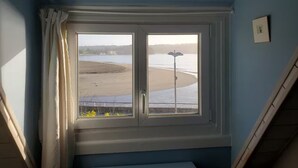 Quarto com uma grande janela com vista para a praia.