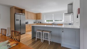 A modern kitchen with a central island, wooden cabinets, and a stainless steel refrigerator.