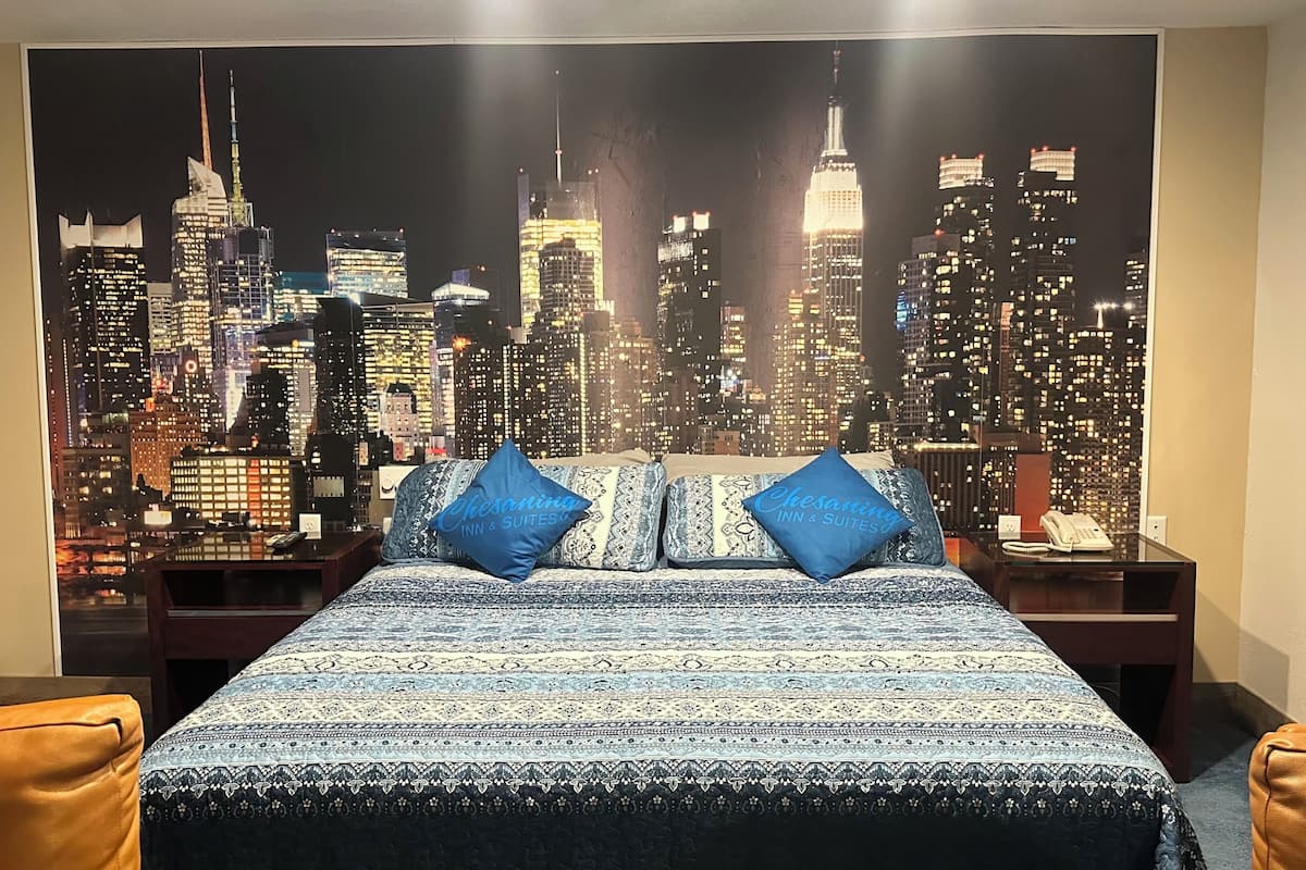 Ein Hotelzimmer mit einem Bett, zwei Kissen, einem Nachttisch, einem Telefon und Blick auf die Stadt.