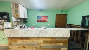A kitchen with a marble countertop, wooden paneling, a wall-mounted American flag, and a door.