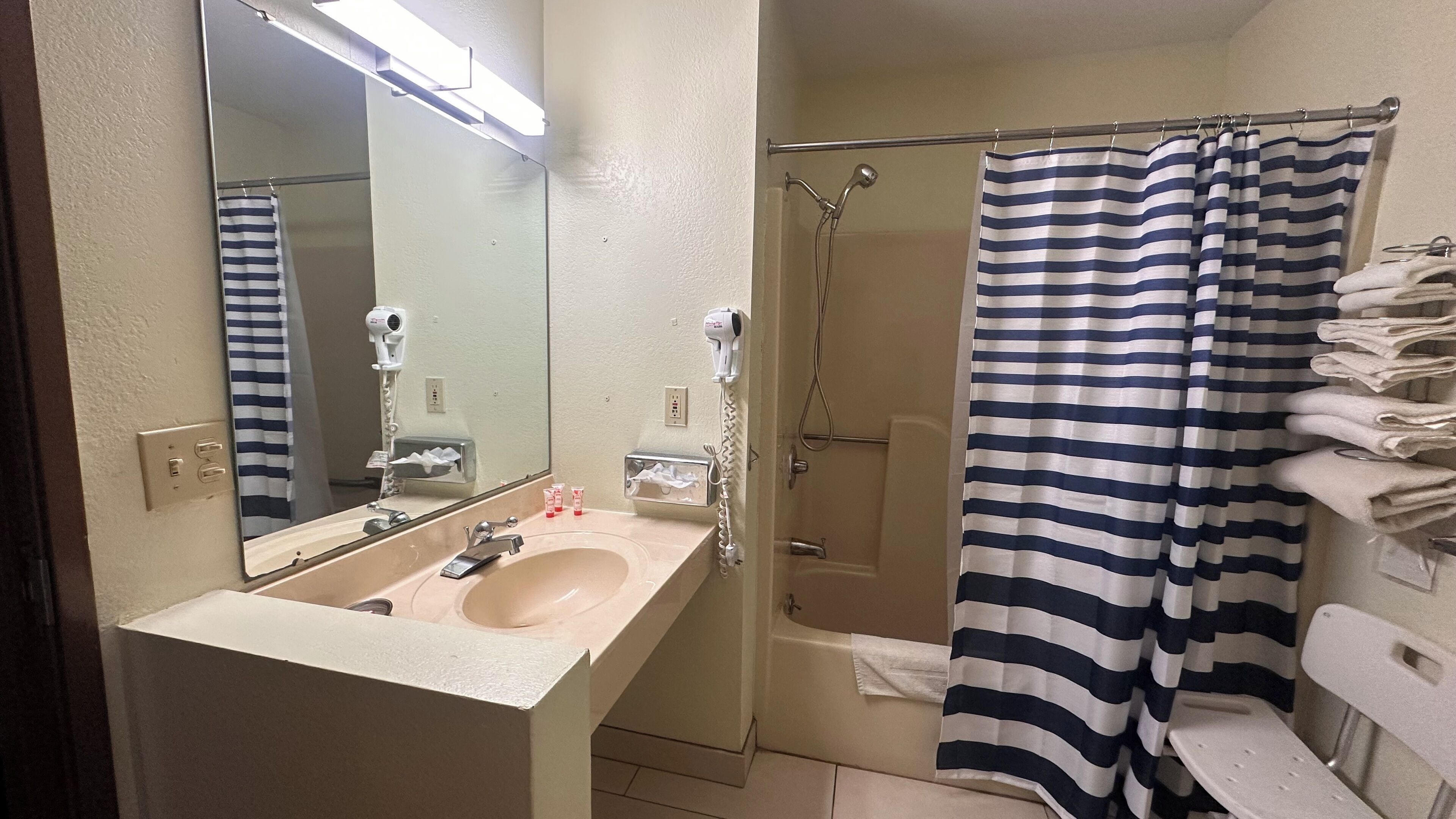 A bathroom with a sink, mirror, towel rack, and a shower curtain.