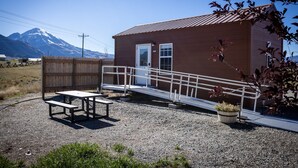Un piccolo edificio con rivestimento in legno, una rampa in metallo e un tavolo da picnic.