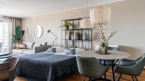 A modern living room with a bed, a round dining table, and a sofa.