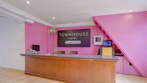 A reception desk with a sign reading 'TOWNHOUSE HOTEL' and a 'Company-Serviced' label. - Luxury Stays With Pool Near Calangute Beach (Calangute)
