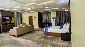 Een hotelkamer met een bed, een bank, een televisie en een bureau.