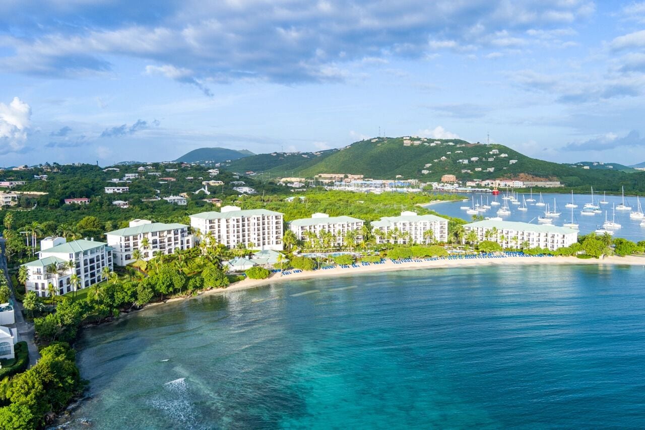 A coastal resort with beachfront villas, a marina, and lush greenery.