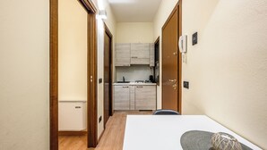 A compact kitchen with wooden cabinets, a refrigerator, and a microwave. - Emilia Studios 2 (Modena)