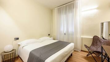 Relax in a serene space with a comfortable bed, a stylish chair, and a large mirror.